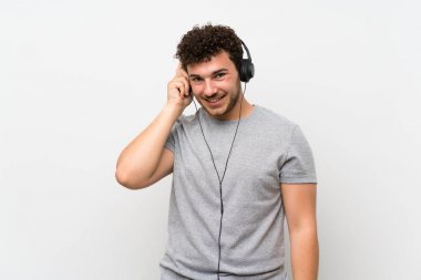 Izole duvar üzerinde kıvırcık saçlı adam kulaklık ile müzik dinlerken