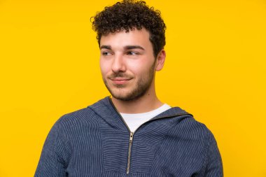 Izole sarı duvar üzerinde genç adam ayakta ve yan bakıyor