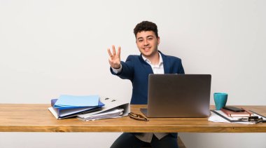 Bir ofiste iş adamı mutlu ve parmakları ile üç sayma