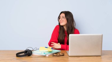 Omuzları kaldırırken şüphe jest yapma bir masada okuyan genç öğrenci kız