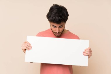 Yakışıklı adam bir kavram eklemek için boş bir beyaz pankart tutan