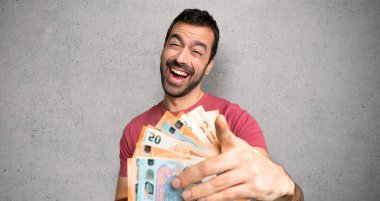 Adam birini parmakla işaret ve dokulu duvar üzerinde çok gülüyor para çok alarak