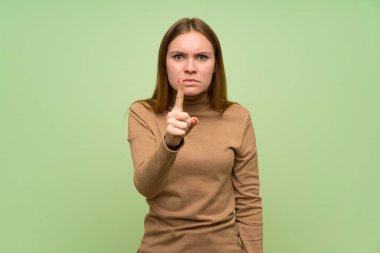 Balıkçı yaka kazaklı genç bir kadın hayal kırıklığına uğramış ve ön tarafı işaret ediyor.