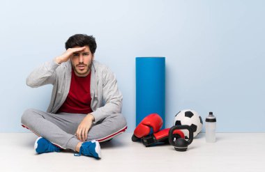 Spor adam bir şey bakmak için el ile uzak lara bakarak yerde oturan