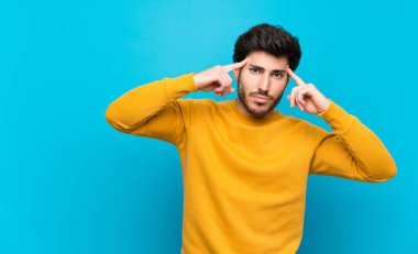 Şüpheleri ve düşünceleri olan izole mavi duvar üzerinde yakışıklı