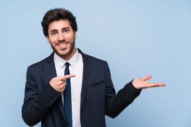 Bir reklam eklemek için avuç üzerinde copyspace hayali tutan izole mavi duvar üzerinde İşadamı