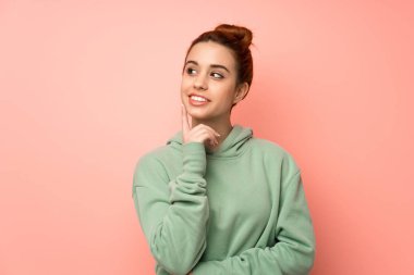 Eşofmanlı genç kızıl saçlı kadın yukarı bakarken bir fikir düşünüyor.