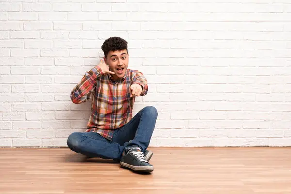 Mladý Muž Sedí Podlaze Gestikuluje Ukazuje Dopředu — Stock fotografie