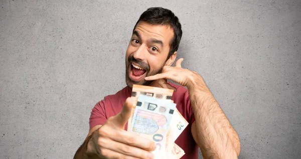 Hombre Tomando Montón Dinero Haciendo Gesto Teléfono Apuntando Frente Pared — Foto de Stock