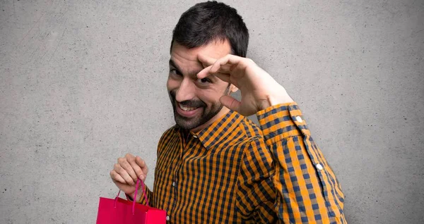 Hombre Con Bolsas Compras Saludando Con Mano Sobre Pared Texturizada — Foto de Stock