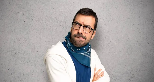 Handsome man with glasses with confuse face expression while bites lip over textured wall