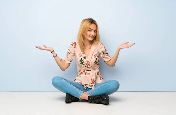 Young Blonde Woman Sitting Floor Making Doubts Gesture — Stock Photo, Image