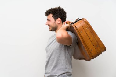 Bir vintage evrak çantası tutan izole duvar üzerinde kıvırcık saçlı adam