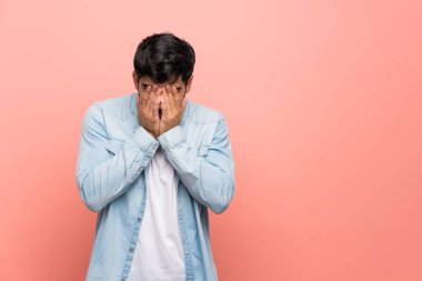 Genç adam yorgun ve hasta ifade ile pembe duvarın üzerinden