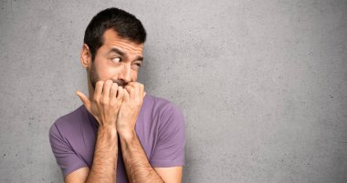 Yakışıklı adam biraz gergin ve dokulu duvar üzerinde ağız ellerini koyarak korkuyor