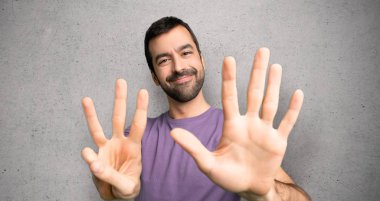 Yakışıklı adam dokulu duvar üzerinde parmakları ile sekiz sayma