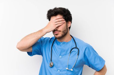 Elleriyle gözleri kaplayan izole beyaz duvar üzerinde Cerrah doktor adam