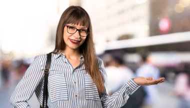 Açık havada bir reklam eklemek için avuç içinde boşaltmak hayali tutan gözlük kadın