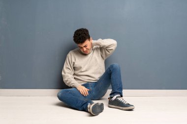 Boyun ağrısı ile yerde oturan genç adam