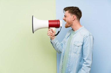 Renkli arka plan üzerinde Redhead adam bir megafon ile bağırıyor