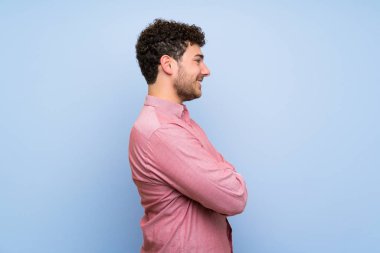 Yanal pozisyonda izole mavi duvar üzerinde kıvırcık saçlı adam