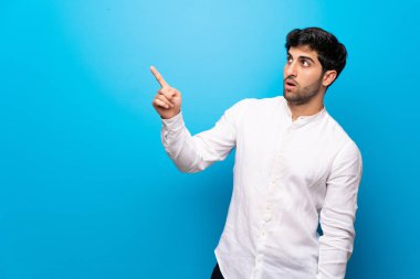 İzole edilmiş mavi duvarın üstündeki genç adam