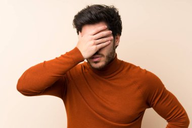 Elleriyle gözleri kaplayan izole duvar üzerinde Yakışıklı