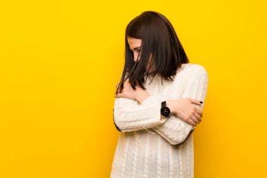 İzole edilmiş sarı duvarlı genç kadın donuyor.