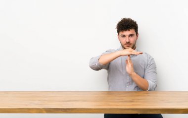 Masası olan genç bir adam, jest yapıyor.