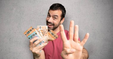 Adam mutlu bir sürü para alarak ve dokulu duvar üzerinde parmakları ile dört sayma