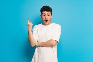 Genç adam mavi arka planda bir fikir düşünüyor.