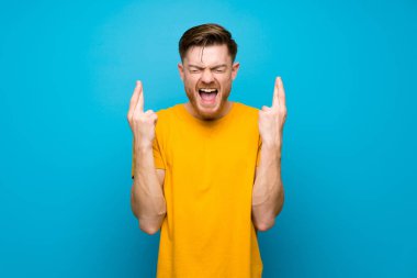 Parmakları geçerken mavi duvar üzerinde Redhead adam