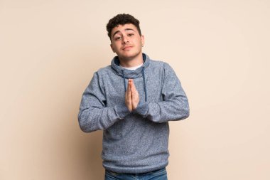 İzole edilmiş duvarın üzerindeki genç adam avuç içlerini bir arada tutuyor. İnsan bir şey ister.