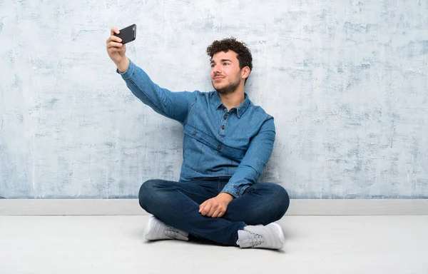Junger Mann Sitzt Auf Dem Boden Und Macht Selfie Mit — Stockfoto