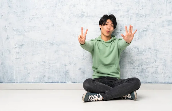 Asiatischer Mann Sitzt Auf Dem Boden Und Zählt Sieben Mit — Stockfoto