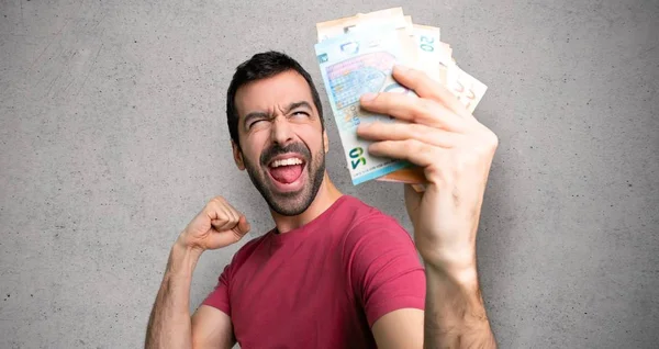 Hombre Tomando Montón Dinero Celebrando Una Victoria Sobre Pared Texturizada — Foto de Stock