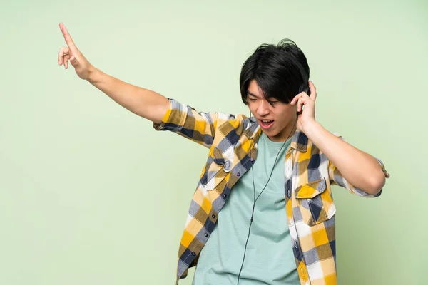 Asiatique Homme Sur Isolé Vert Mur Écouter Musique Avec Casque — Photo