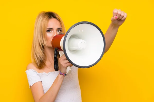 Jonge Blonde Vrouw Geïsoleerde Gele Muur Schreeuwen Door Een Megafoon — Stockfoto
