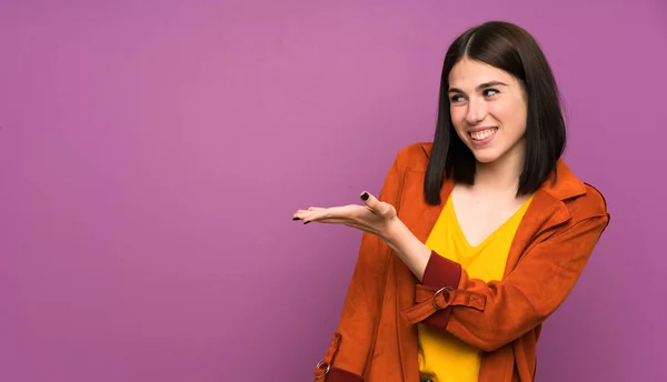 Young Woman Coat Isolated Purple Background Extending Hands Side Inviting — Stock Photo, Image