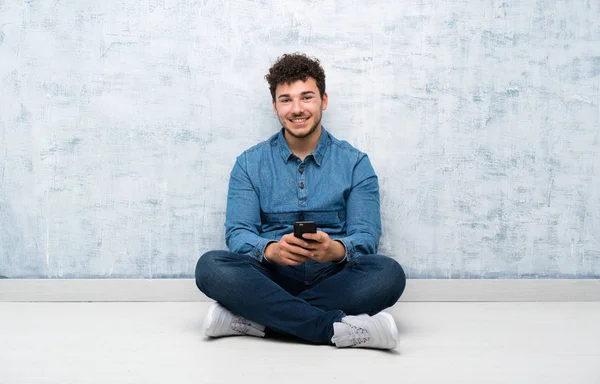 Junger Mann Sitzt Mit Handy Auf Dem Boden — Stockfoto