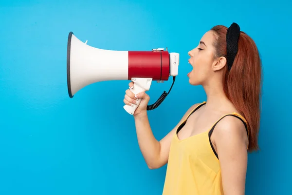 Jonge Roodharige Vrouw Blauwe Achtergrond Schreeuwen Door Een Megafoon — Stockfoto