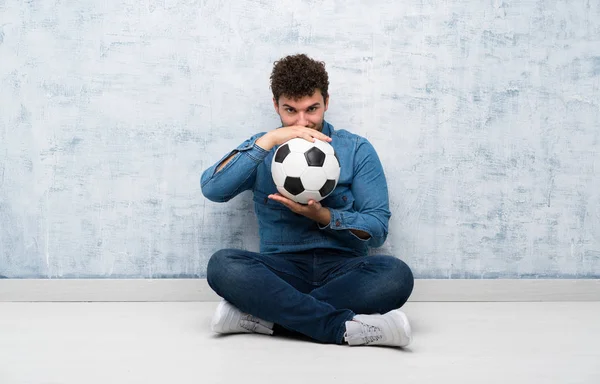 Młody Mężczyzna Siedzi Podłodze Trzymając Piłkę Nożną — Zdjęcie stockowe