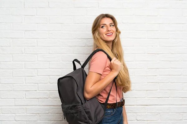 Jovem Loira Sobre Parede Tijolo Branco Com Mochila — Fotografia de Stock