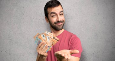 Adam, dokulu duvara bir reklam eklemek için palmiye üzerinde boşaltmak hayali tutan bir sürü para alıyor