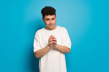 Mavi arka plandaki genç adam bir şeyler planlıyor.