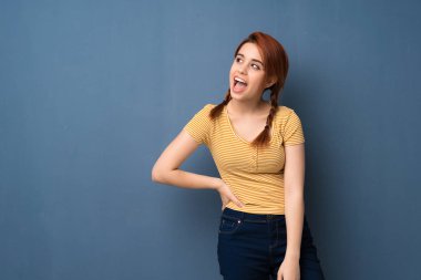 Üzerinde mavi arka plan gülümseyen genç Kızıl saçlı kadın