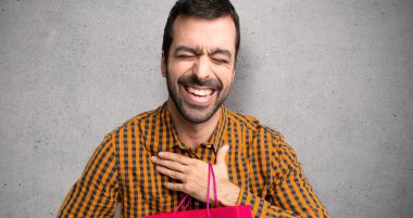 Dokulu duvar üzerinde göğüs ellerini koyarken alışveriş çantaları ile adam çok gülümsüyor