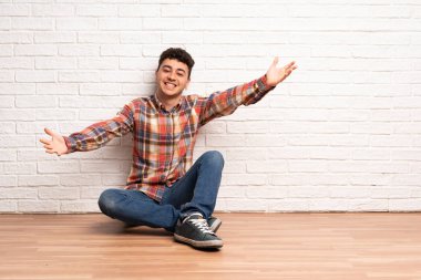 Zemin sunan üzerinde oturan ve el ile gelmek davet genç adam