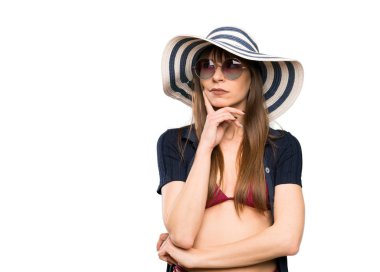 Bikinili genç bir kadın izole edilmiş beyaz bir arka plan üzerinde düşünüyor.