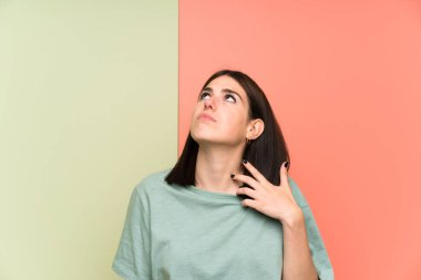 Izole renkli duvar ayakta ve bir fikir düşünme üzerinde genç kadın